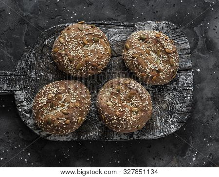 Multigrain Multiseed Fitness Buns On Rustic Wooden Chopping Board On Dark Background, Top View