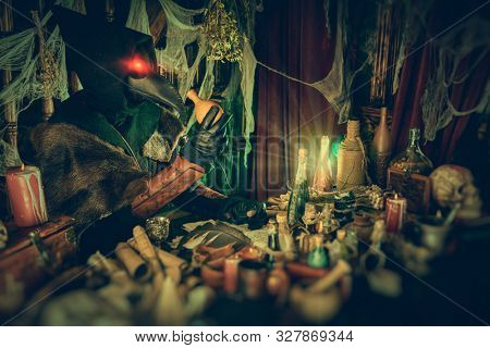The plague doctor is working at his desk, inventing a cure for bubonic plague. The atmosphere of mysticism. Historical reenactment. Halloween. 