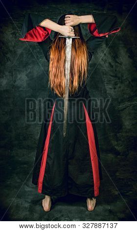 Full Length Portrait Of Young Long Haired Woman Wearing A Medieval Costume. Standing Pose With A Swo