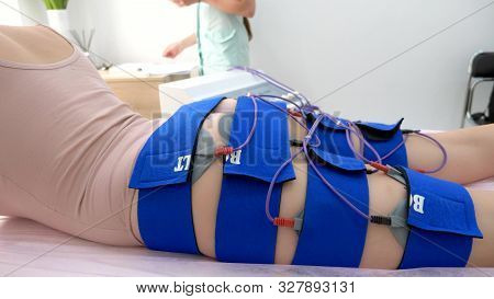 The Girl Lies On The Couch And Receives The Procedure Of Myostimulation On Her Legs And Buttocks In 