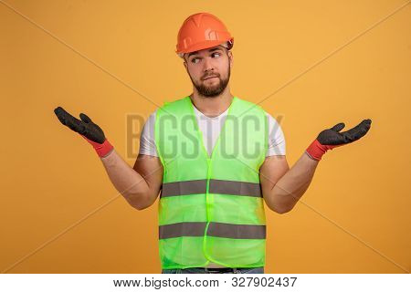 Man Builder Wears Building Helmet And Waistcoat, Spreads Hands In Confusing Gesture, Has No Idea How