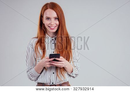 Cheerful Redheared Woman Businesswomen In A Striped Shirt Showing Blank Smartphone Screen White Back
