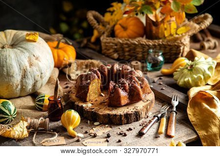Tasty Homemade Baked Pumpkin Bundt Cake With Chocolate On Top Stands On Wooden Board On Rustic Table