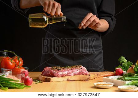 Chef Cooks Pork Steak. Pouring Oil On The Background With Vegeta