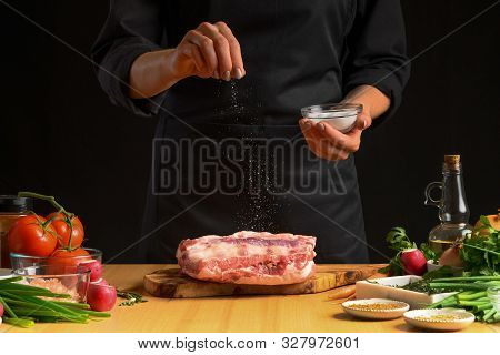 Chef Cooks Pork Ribs. Sprinkling With Salt On A Background With
