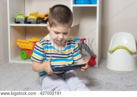 A Little Boy 3-4 Years Old Looks Into The Screen Of The Tablet. Cartoons For Children, Screen Time, 