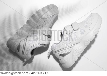 Top View Macro Two White Sneakers With Hard Summer Sun Shadows From A Palm Tree Or Fern On An Isolat