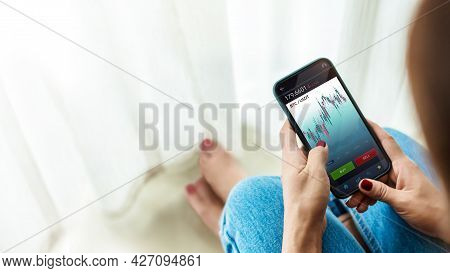Cryptocurrency Investment Concept. Person Using Mobile Phone At Home To Buy And Sell Bitcoin Via Onl