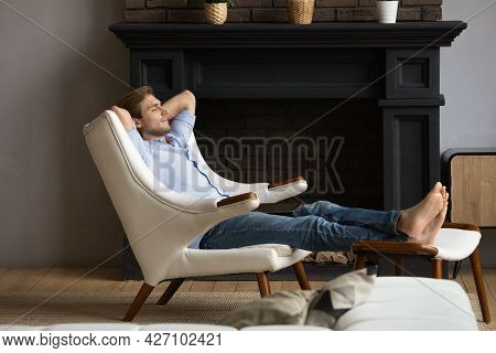 Carefree Young Male Resting In Capacious Armchair At Luxury Apartment