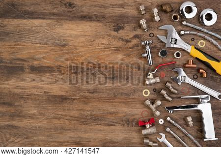 Plumber tools and spare parts on wooden background, top view, flat lay with copy space