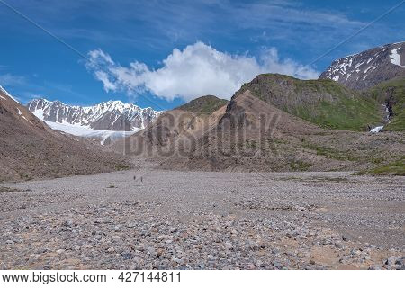 Amazing Landscape With Glacier, Mountains, Stone Valley And Hikers Walking To The Glacier Along A Mo