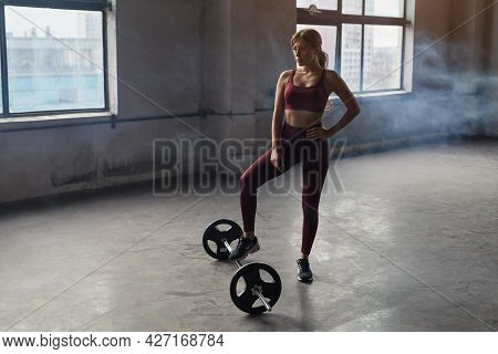 Full Body Of Strong Confident Athletic Female Standing Near Barbell While Preparing For Weightliftin