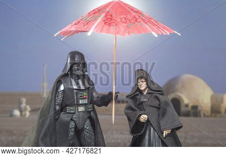 JUNE 12 2021: Humor image, Star Wars Sith Lord Darth Vader and Emperor Palpatine on Tatooine with sun umbrella - Hasbro action figure