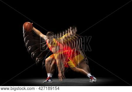 One Young Basketball Player Training With Ball Isolated On Dark Background With Stroboscope Effect. 