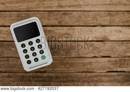 Eftpos machine on a wooden table with design space aerial view