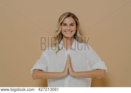 Happy Cute Blond Feamle In White Shirt Pressing Palms Together In Pray, Namaste Or Saying Please Ges