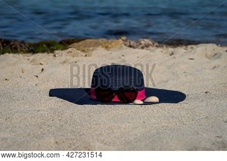 Decoration Of A Sun Hat With Sunglasses And Seashells On The Beach. Summer Decoration.