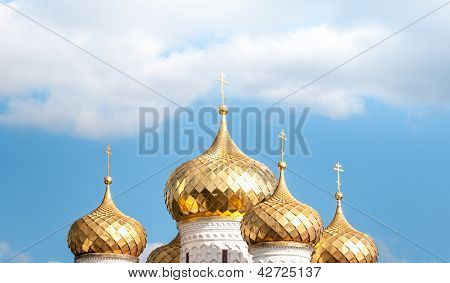Golden domes of russian church against blue sky.