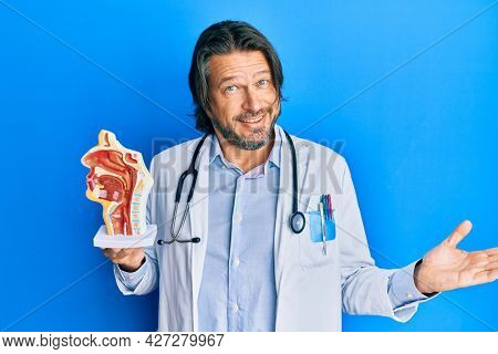 Middle age handsome otologist doctor man holding medical model celebrating achievement with happy smile and winner expression with raised hand 
