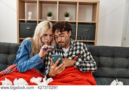 Young ill couple having medical teleconsultation using smartphone at home.