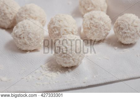 Coconut Balls On A White Table With A White Napkin, Round Sweet Candies  With Coconut Flakes, Vegan 