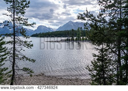 View Of Jackson Lake At Colter Bay In Grand Teton National Park, Naturally Framed By Trees On The La