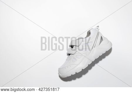 Top View One White Unisex Running Shoe On The Side With Hard Shadows In The Center Isolated On A Whi