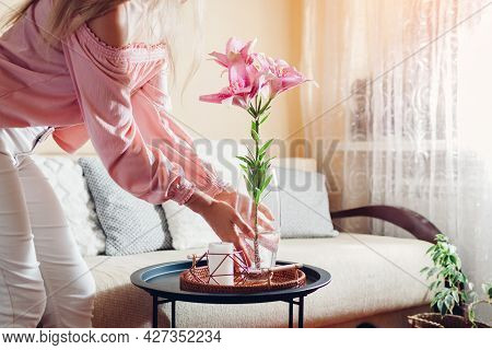 Woman Puts Vase With Pink Lily Flowers On Table. Housewife Taking Care Of Coziness At Home. Interior