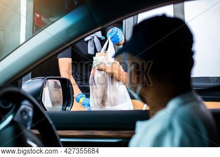 Selective Focus To Hand Of Staff Wearing Medical Glove And Mask  To Handed A Food To Customer. Drive