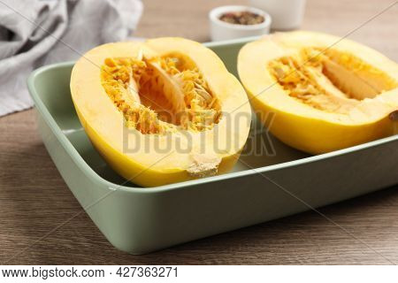 Halves Of Fresh Spaghetti Squash In Baking Dish On Wooden Table, Closeup. Cooking At Home