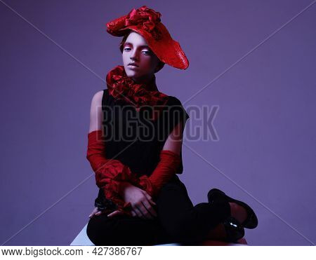 Beautiful child girl in a stylish fashionable suit - red hat, scarf, bracelet, neon light, fashion concept