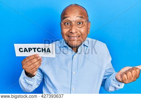 Middle age latin man holding captcha message paper screaming proud, celebrating victory and success very excited with raised arm 