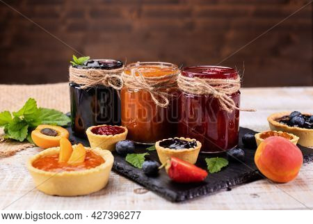 Delicious summer fruits jam - various berries and assorted jams on wooden table