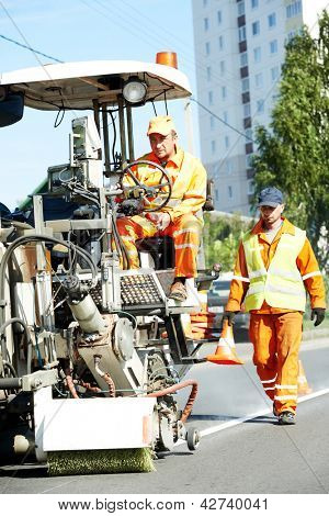 dos trabajadores de la construcción con roaad marcadora en marcas en el pavimento asfalto road