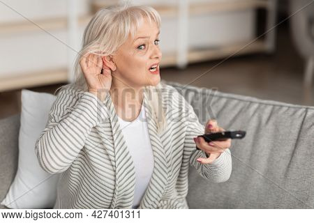 Hearing Problems. Mature Woman Watching Television Sitting On Couch