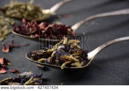 Various Kinds Of Dry Tea Bancha Green, Hibiscus, Butterfly Pea Flower Tea In Spoons On The Table