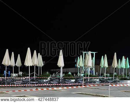 Night Empty Beach With Sun Loungers And Folded Umbrellas Fenced Off With A Barrier Tape