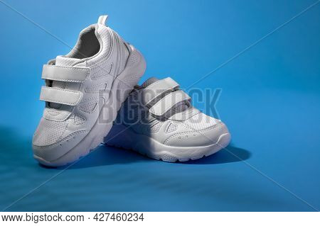 White Childrens Running Shoes With Velcro Fasteners For Easy Shoeing On A Purple Background With Fer