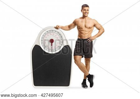 Shirtless young fit man leaning on a big weigth scale isolated on white background 