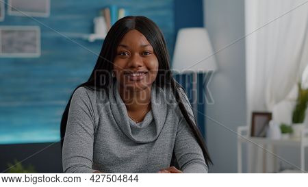 Portrait Of Confident Student Relaxing At Desk Table In Living Room Looking Into Camera Smiling Duri
