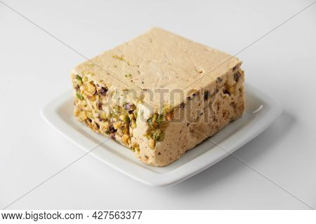Organic Halva With Pistachios On A White Plate Isolated On White. Traditional Middle Eastern Sweets.