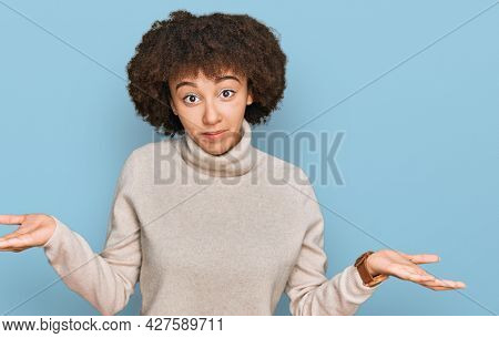 Young hispanic girl wearing wool winter sweater smiling showing both hands open palms, presenting and advertising comparison and balance 