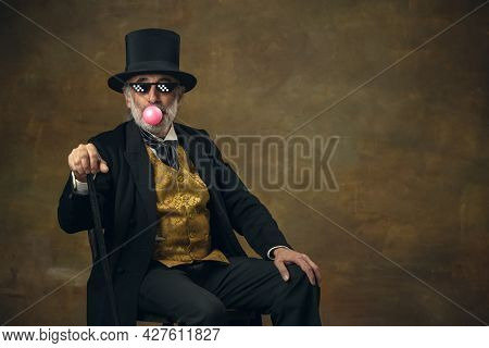 Cute Senior Smiling Man, Gentleman, Aristocrat Or Actor Watching Movie Isolated On Dark Vintage Back
