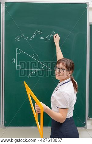 School Teacher Young Woman In The Class At The Blackboard Draws A Triangle With A Ruler. Portrait. C
