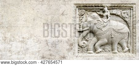 Grunge background with stone texture and bas-relief with elephant rider. Horizontal banner with ancient ornament. Copy space for text. Mock up template