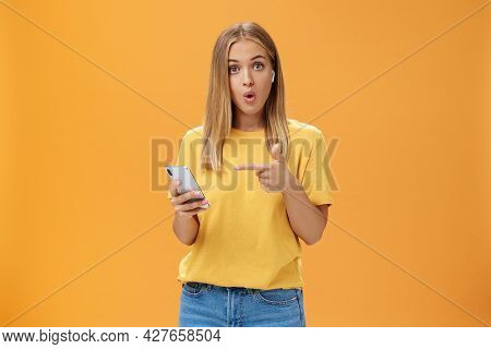 Wman Impressed By Wireless Earphones Connecting To Smartphone Themselves Pointing At Device Screen Q
