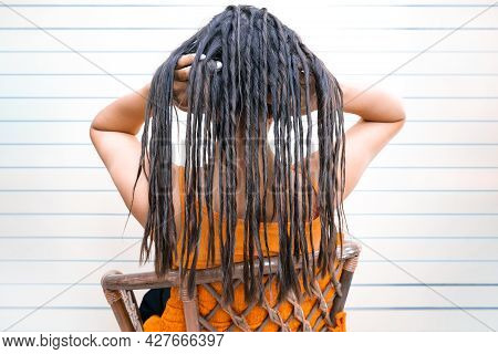 Young Woman With Dreadlocks. False Dreadlocks On The Curling Iron. Holds In Hand And Smiles