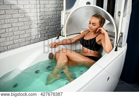 Pretty Woman In Black Swimsuit Receiving Vibro Massage While Relaxing In The Bathtub In A Spa Capsul