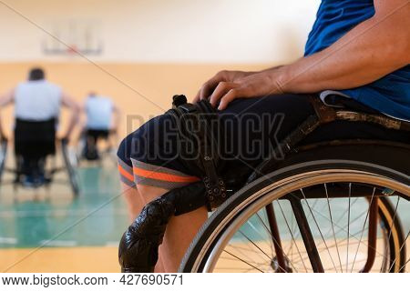 Close up photo of wheelchairs and handicapped war veterans playing basketball on the court