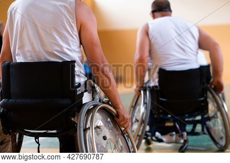 Close up photo of wheelchairs and handicapped war veterans playing basketball on the court